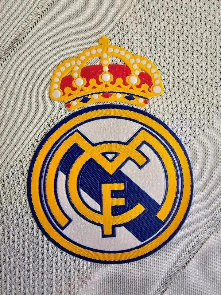Crest detail of Real Madrid with crown logo and CF initials in blue and yellow.
