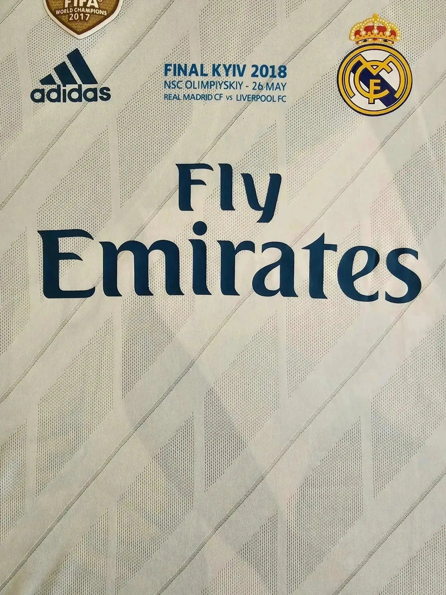 Crest detail showing Real Madrid CF badge, Fly Emirates sponsor, and adidas logo on white background.