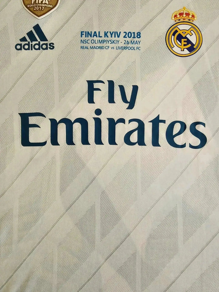 Crest detail showing Real Madrid CF badge, Fly Emirates sponsor, and adidas logo on white background.