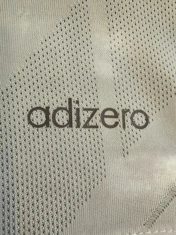 Close-up of adizero text on a gray patterned soccer jersey fabric.