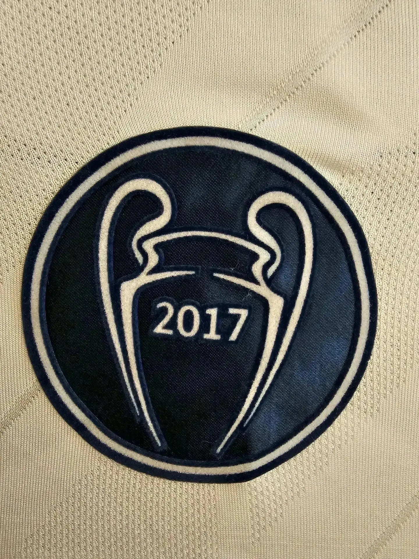 Crest detail featuring the UEFA Champions League trophy with 2017 on a white background.