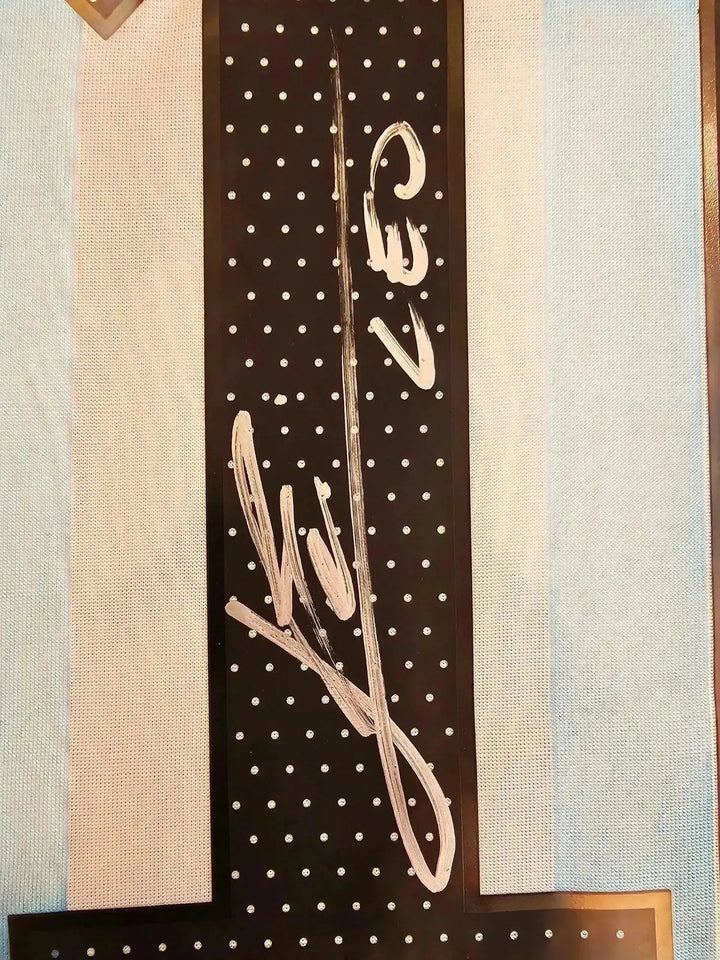 Signature detail of a signed Lionel Messi soccer jersey featuring blue and white stripes.