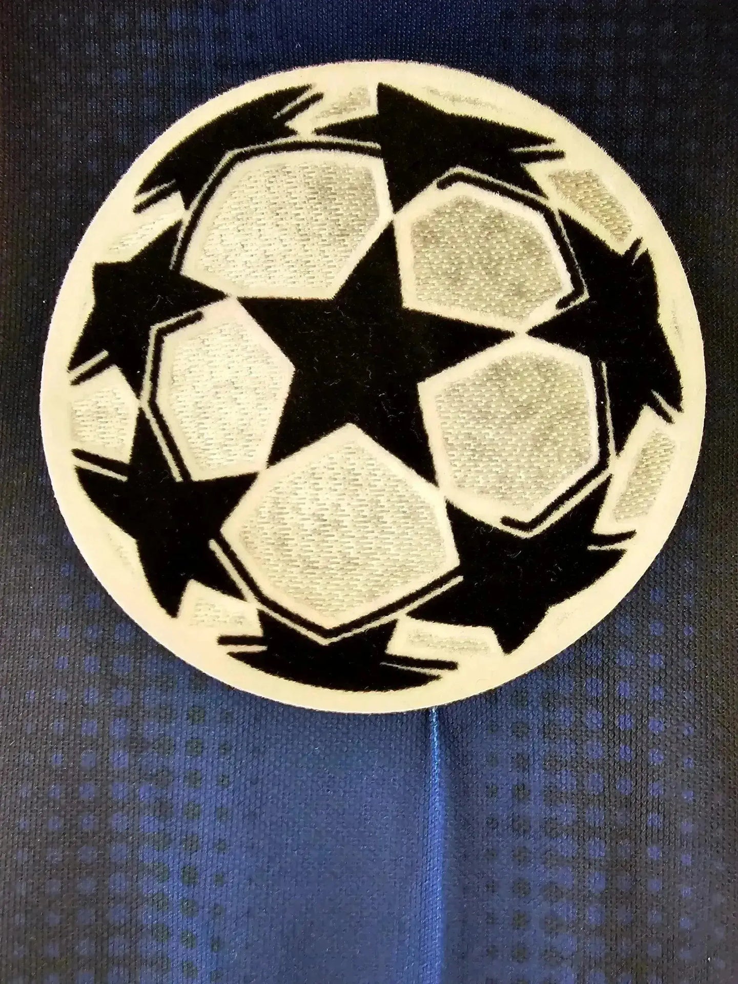 Crest detail featuring UEFA Champions League ball with black stars on a blue background.