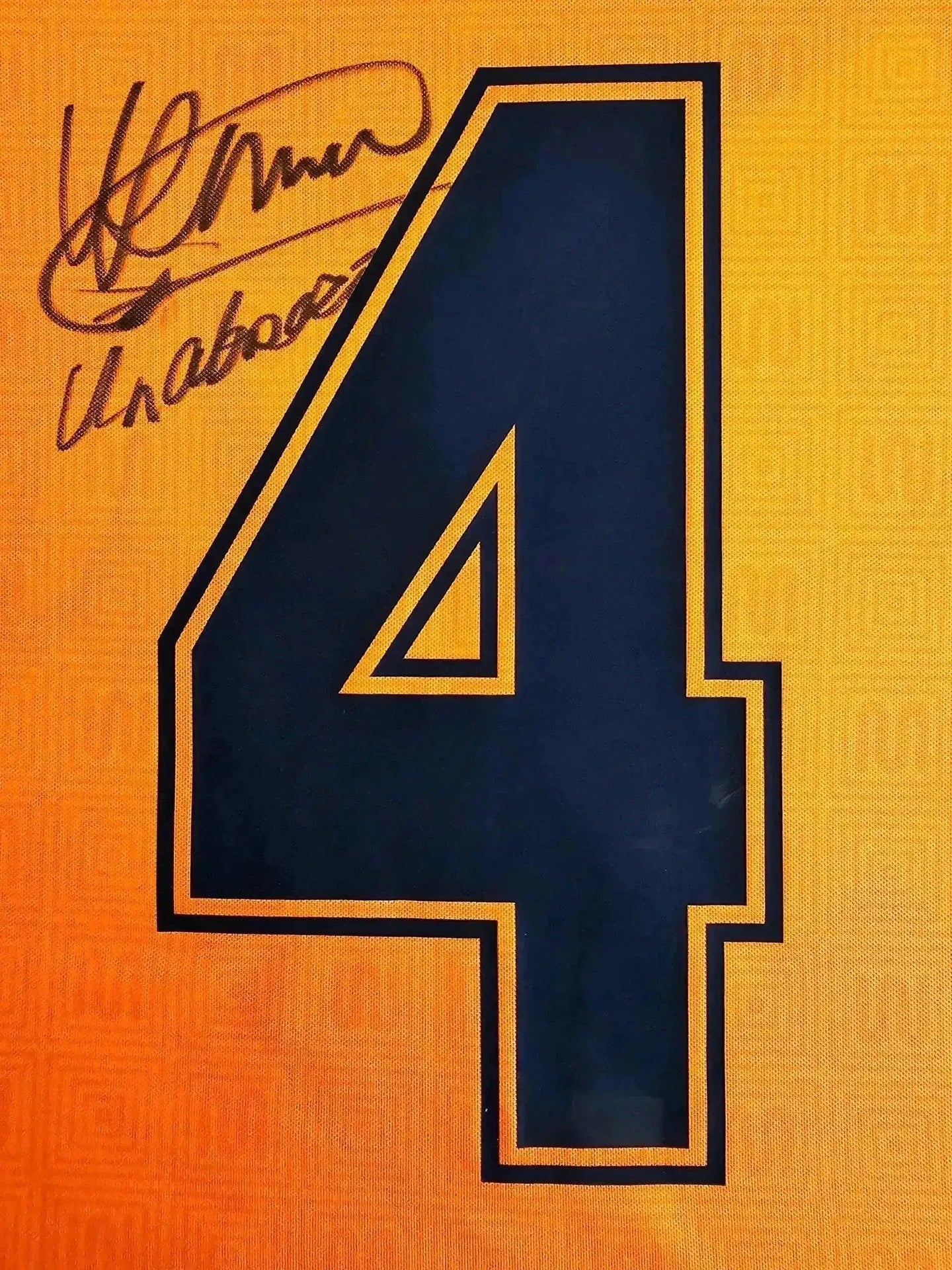 Detail view showing signature of Ronald Koeman above No. 4 on an orange Barcelona shirt.