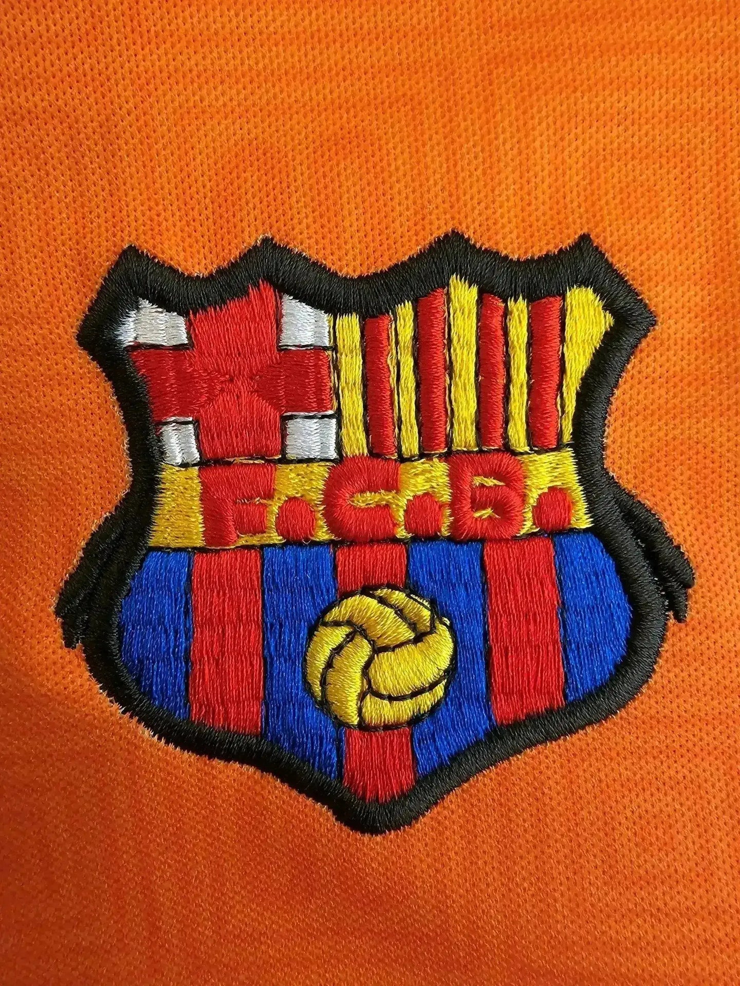 Close-up of the F.C. Barcelona crest featuring red and blue stripes, yellow and red vertical bars, and a football.
