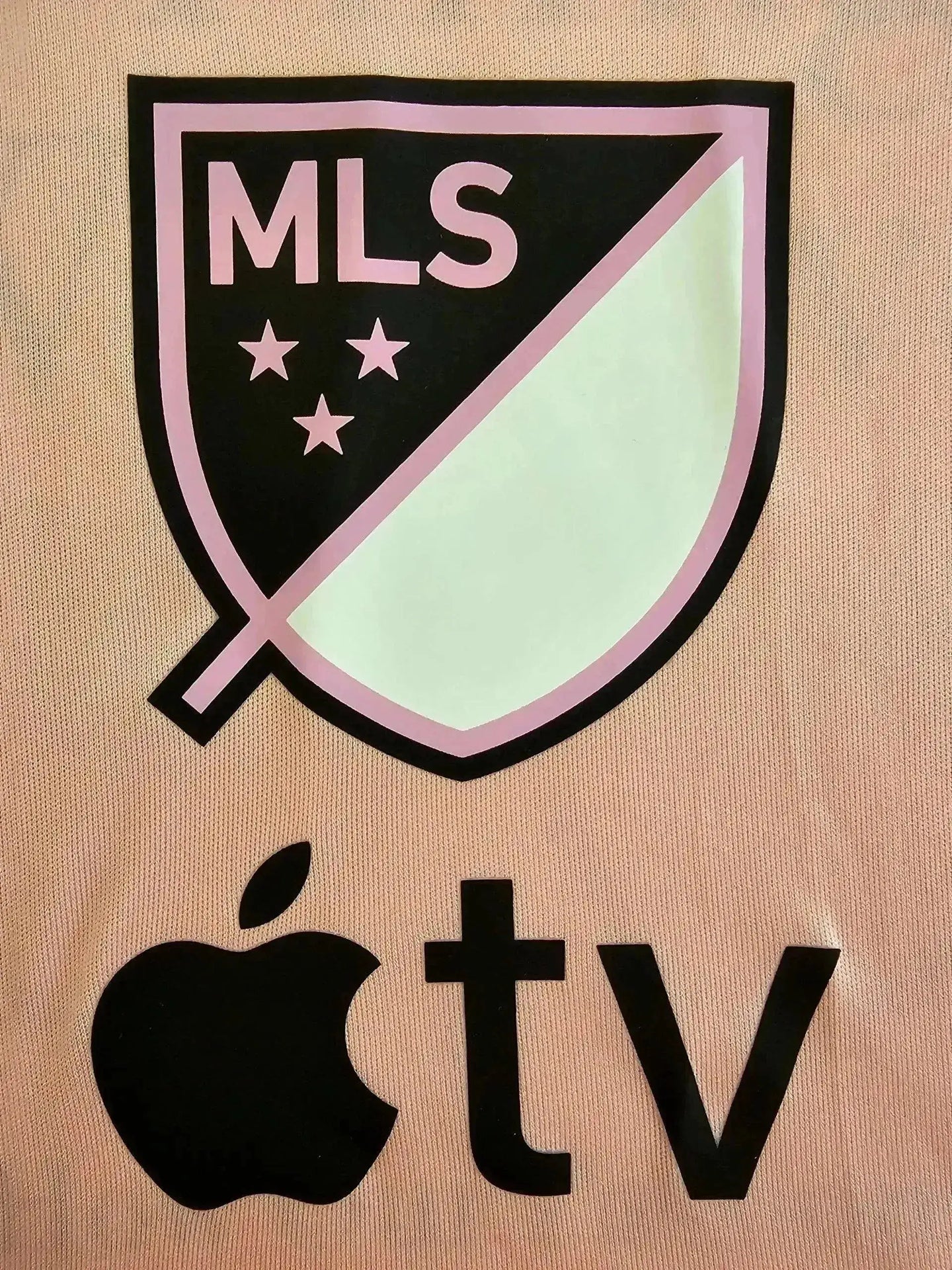 MLS crest with three stars above and black apple TV logo on a pink background.