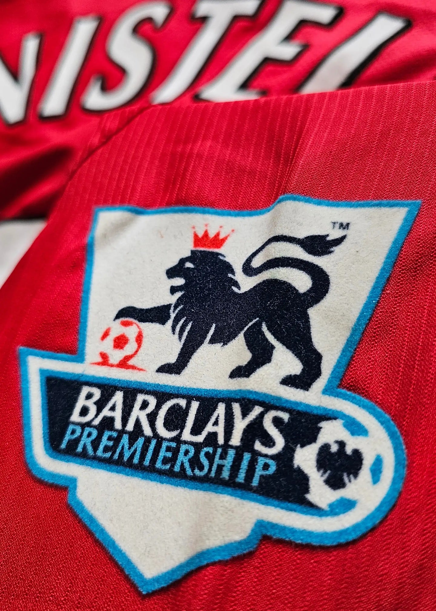 Close-up of the crest detail featuring the Barclays Premiership logo on a red shirt.