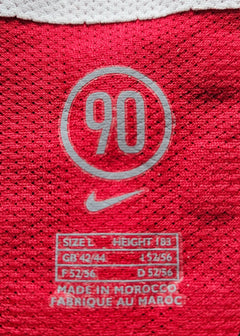 Detail showing '90' logo, Nike branding, and size information with red fabric background.