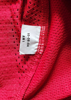 Red mesh fabric with care label showing text: 10-08-04 AM1.