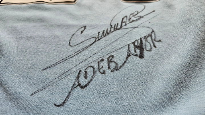 Close-up of a signature of Emmanuel Adebayor on a textured surface.