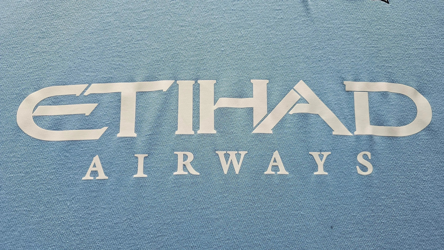 Close-up of the ETIHAD AIRWAYS sponsor on a blue soccer jersey.