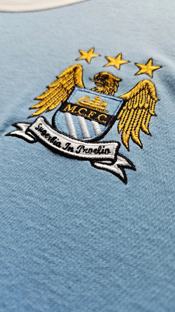 Manchester City FC logo on a light blue background.