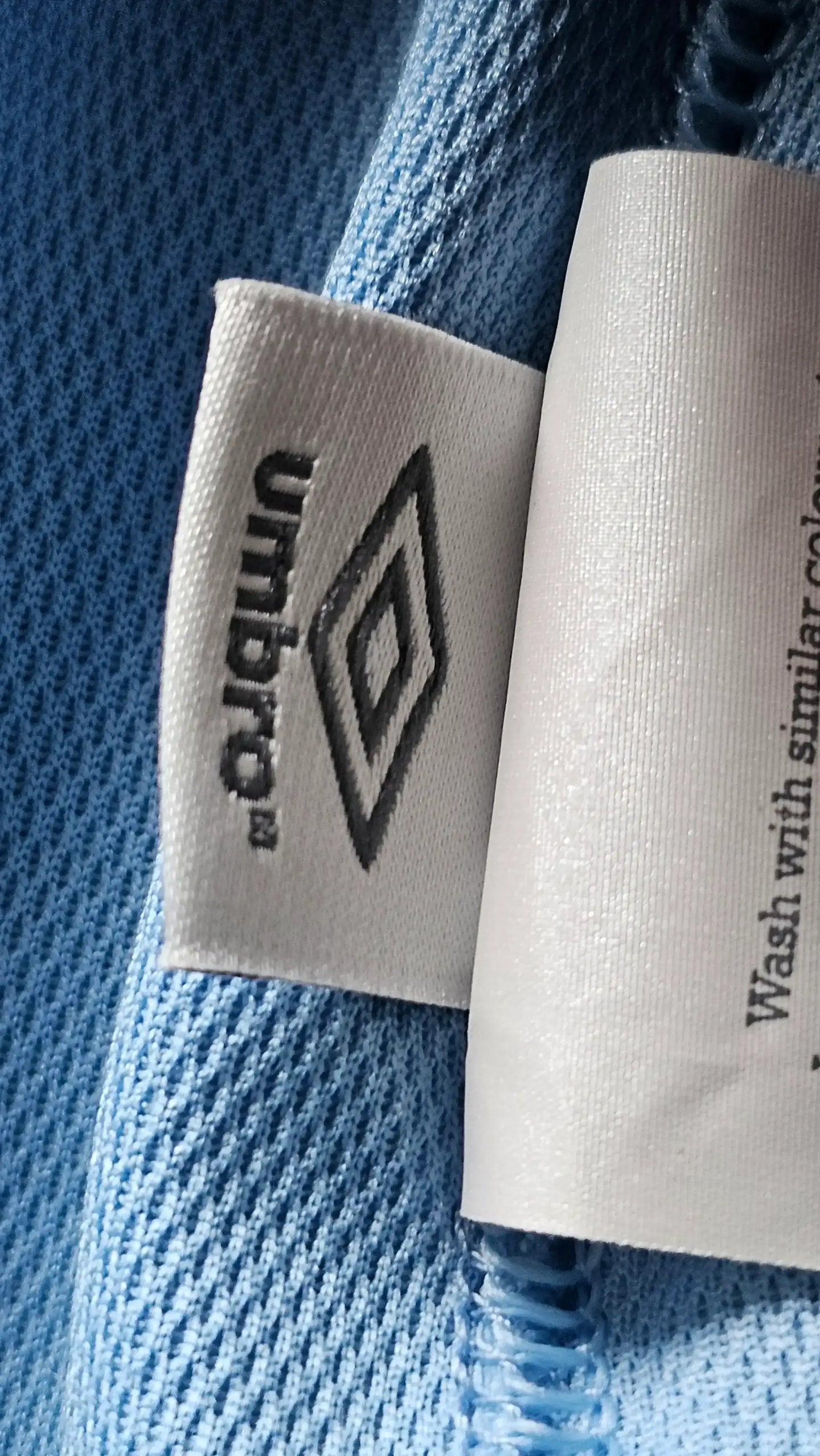 Close-up of the white and black Umbro label on a blue fabric.