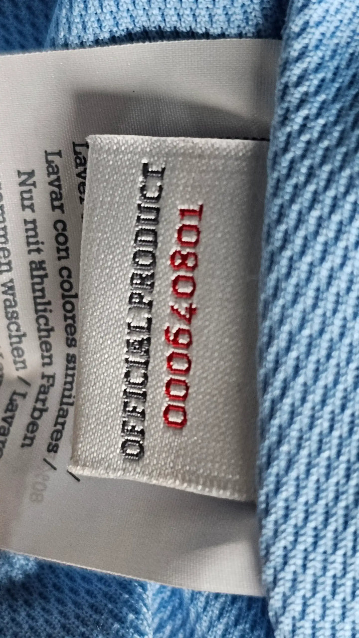 Care label showing 'OFICIAL PRODUCT' and '108079000' in red and black stitching.