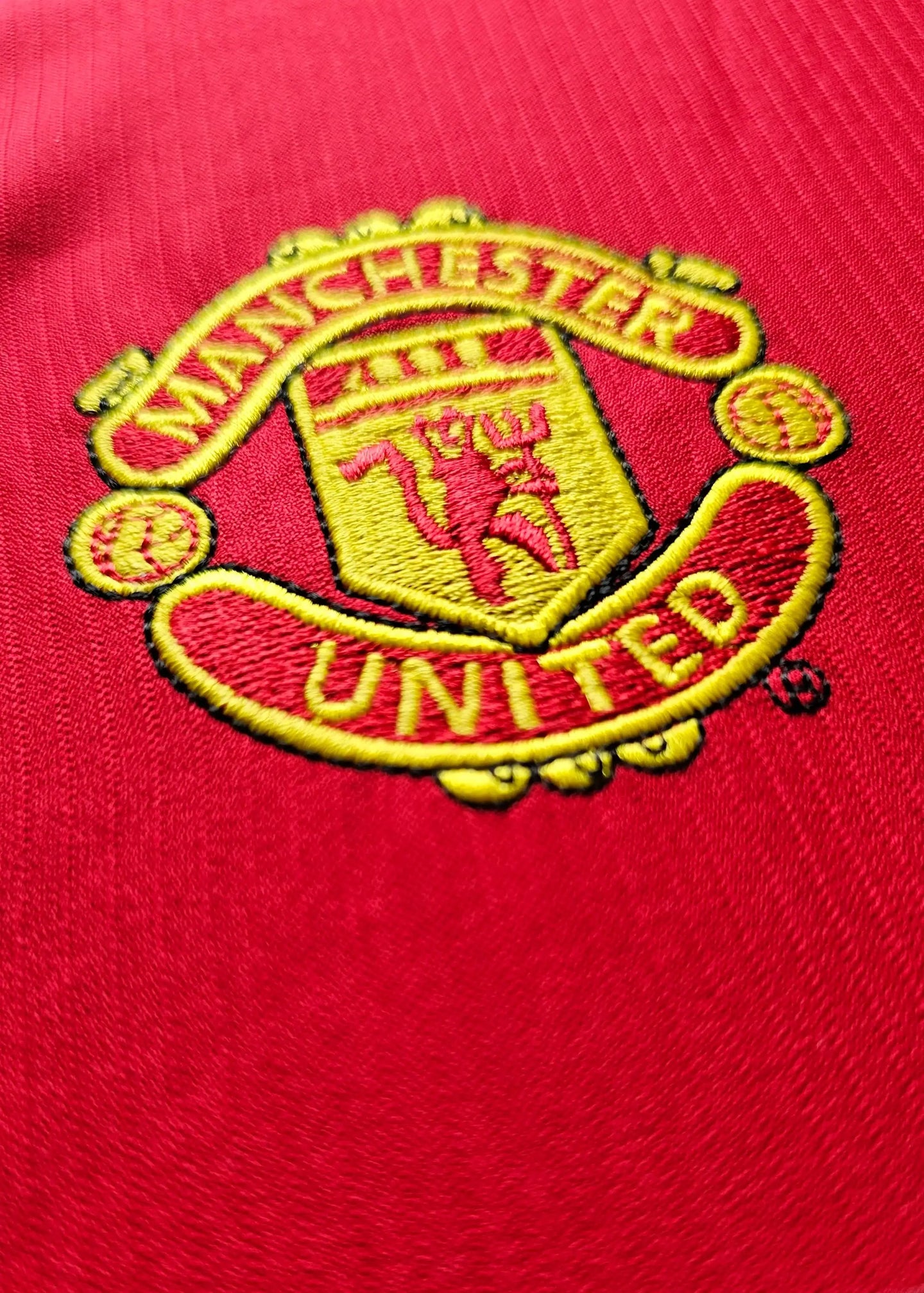 Close-up of Manchester United crest featuring the club name and emblem on a red background.