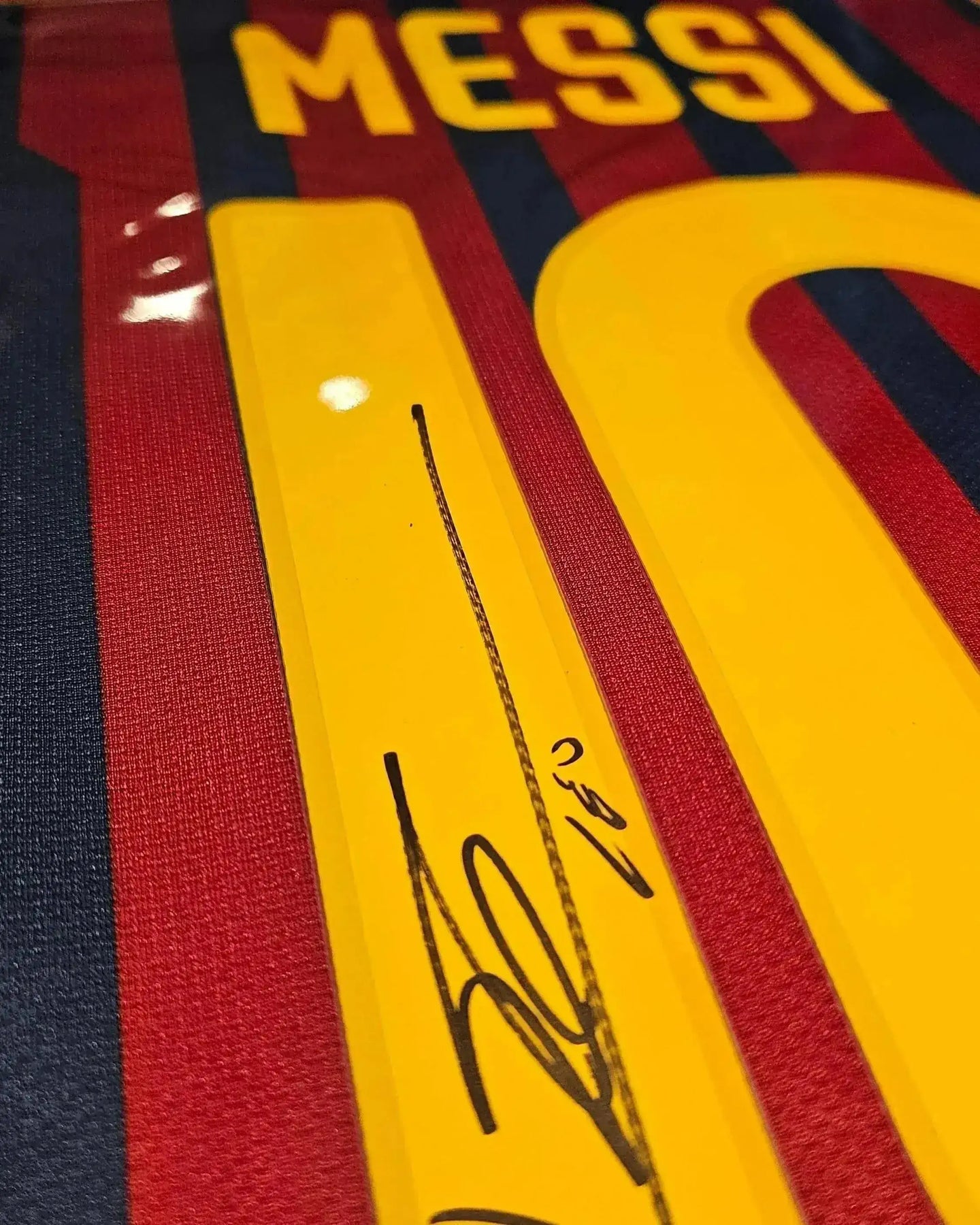 Signature of Messi on the No. 10 FC Barcelona soccer jersey, featuring red and blue stripes.