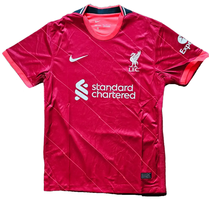 Front view of a signed Liverpool F.C. football shirt featuring the crest and 'standard chartered' sponsor.