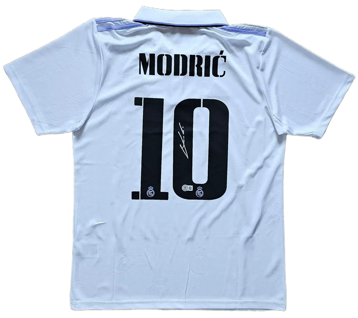 Back view featuring Modrić, No. 10 and a visible signature on a white football shirt.