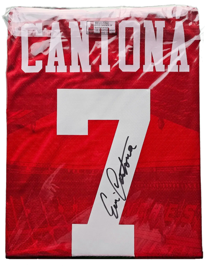 Back view showing Cantona, No. 7, and signature on red football shirt.