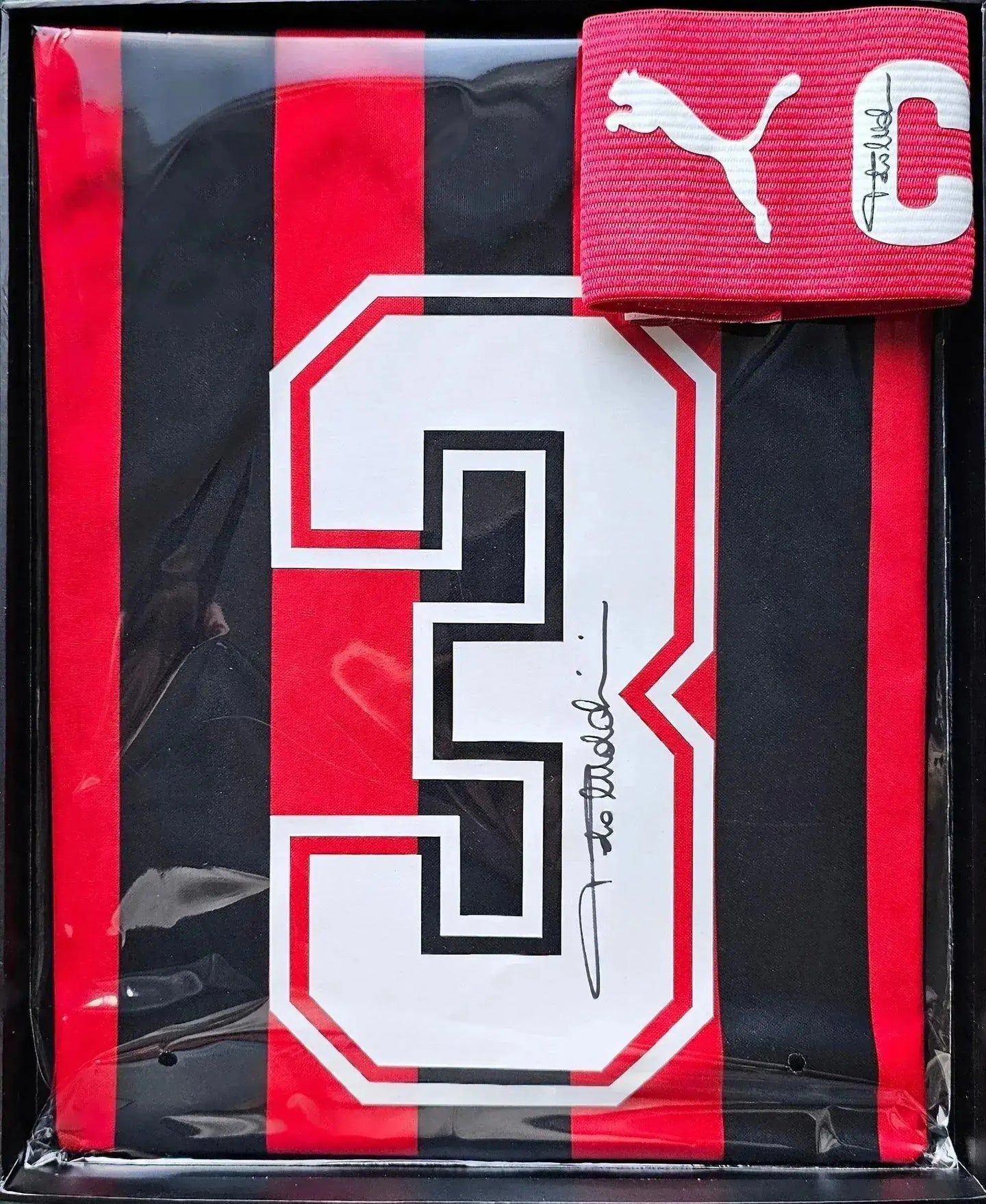 Detail view showing No. 3 and signature on AC Milan football shirt with red and black stripes.