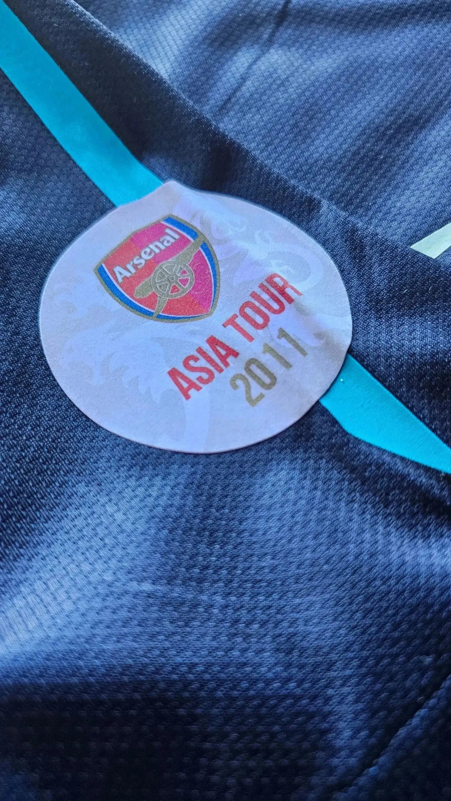 Detail showing Arsenal crest and Asia Tour 2011 badge on Navy soccer jersey.