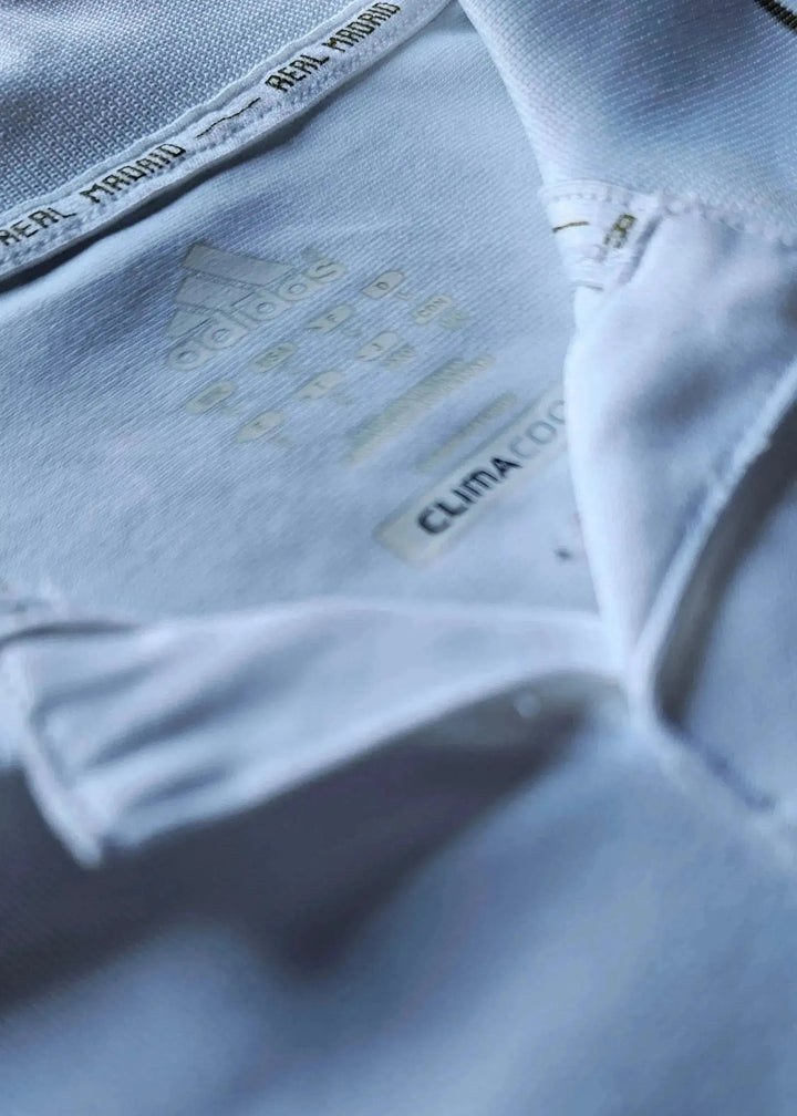 Close-up of Real Madrid label with adidas logo and ClimaCool text on the signed football shirt.