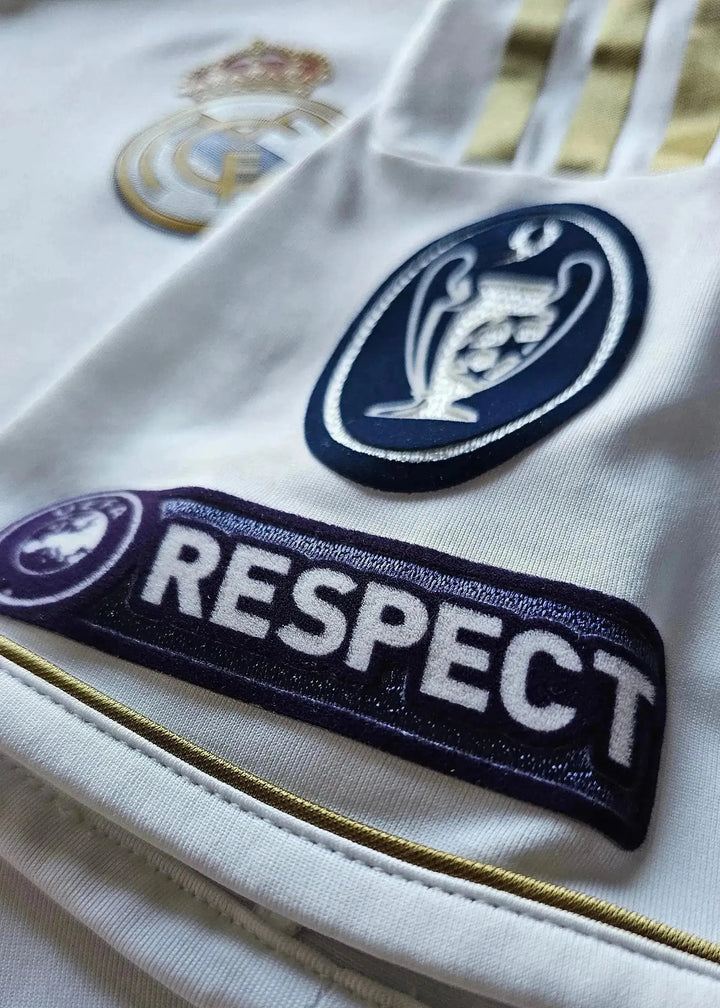 Close-up view showing Real Madrid crest and UEFA Respect badge on the signed football shirt.