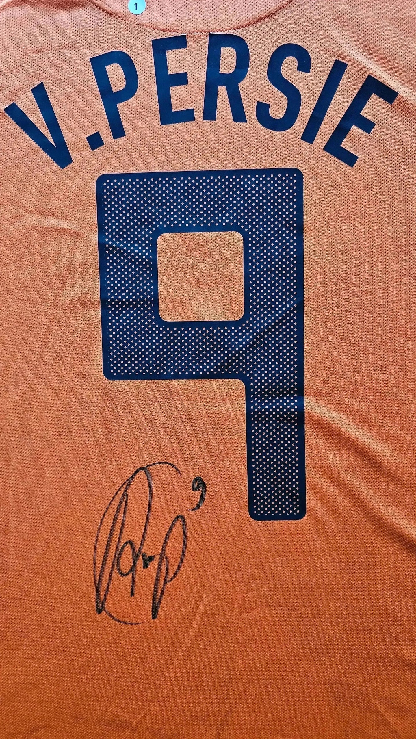 Back view showing V. Persie, No. 9 and a signature in black on an orange football shirt.