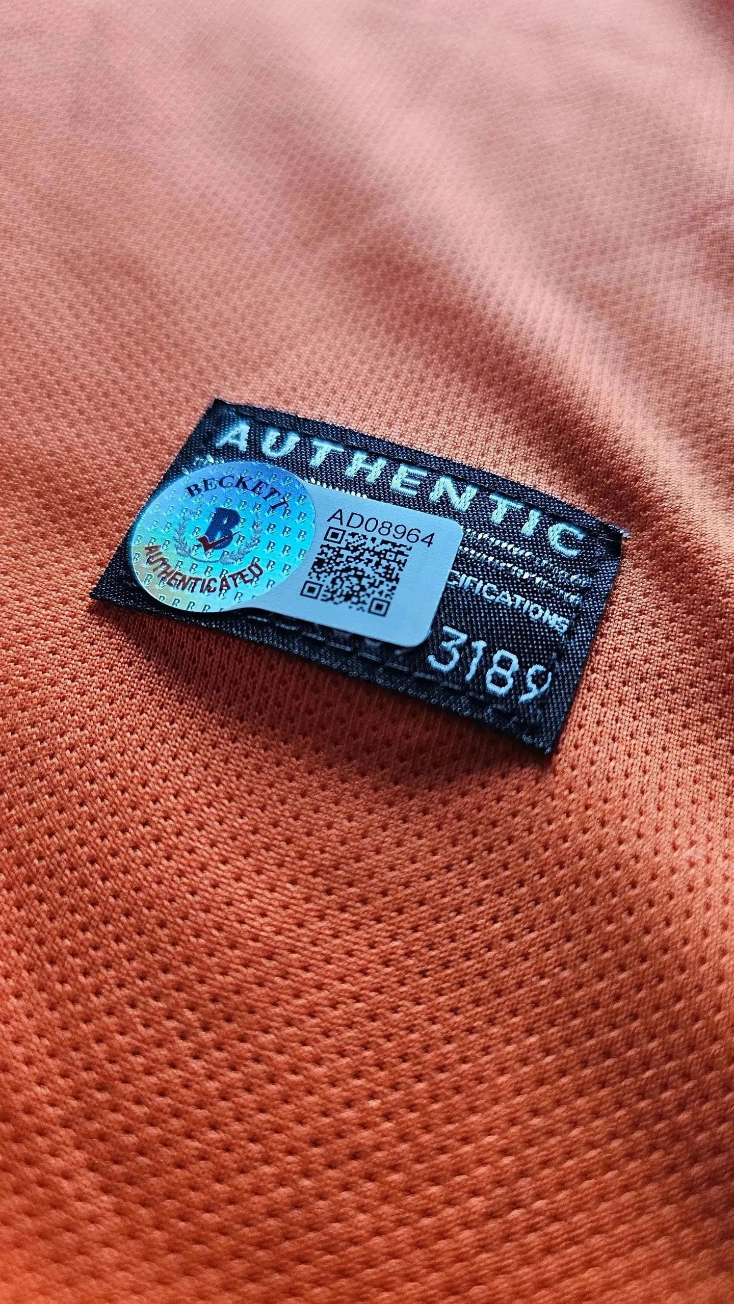 Authentic tag detail with serial number and Beckett certification on orange fabric.