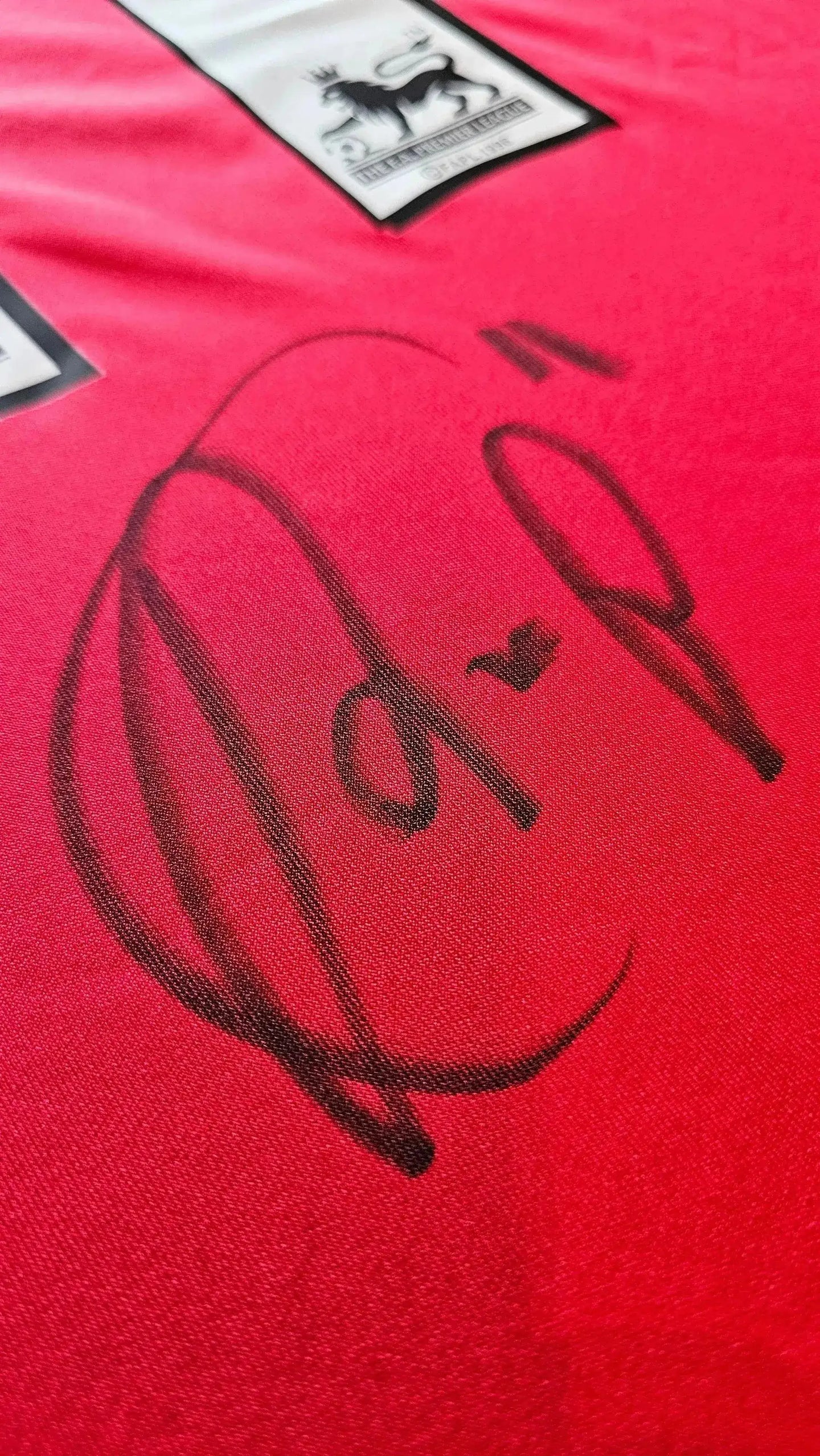 Signature detail of Robin van Persie on red Arsenal football shirt with crest.
