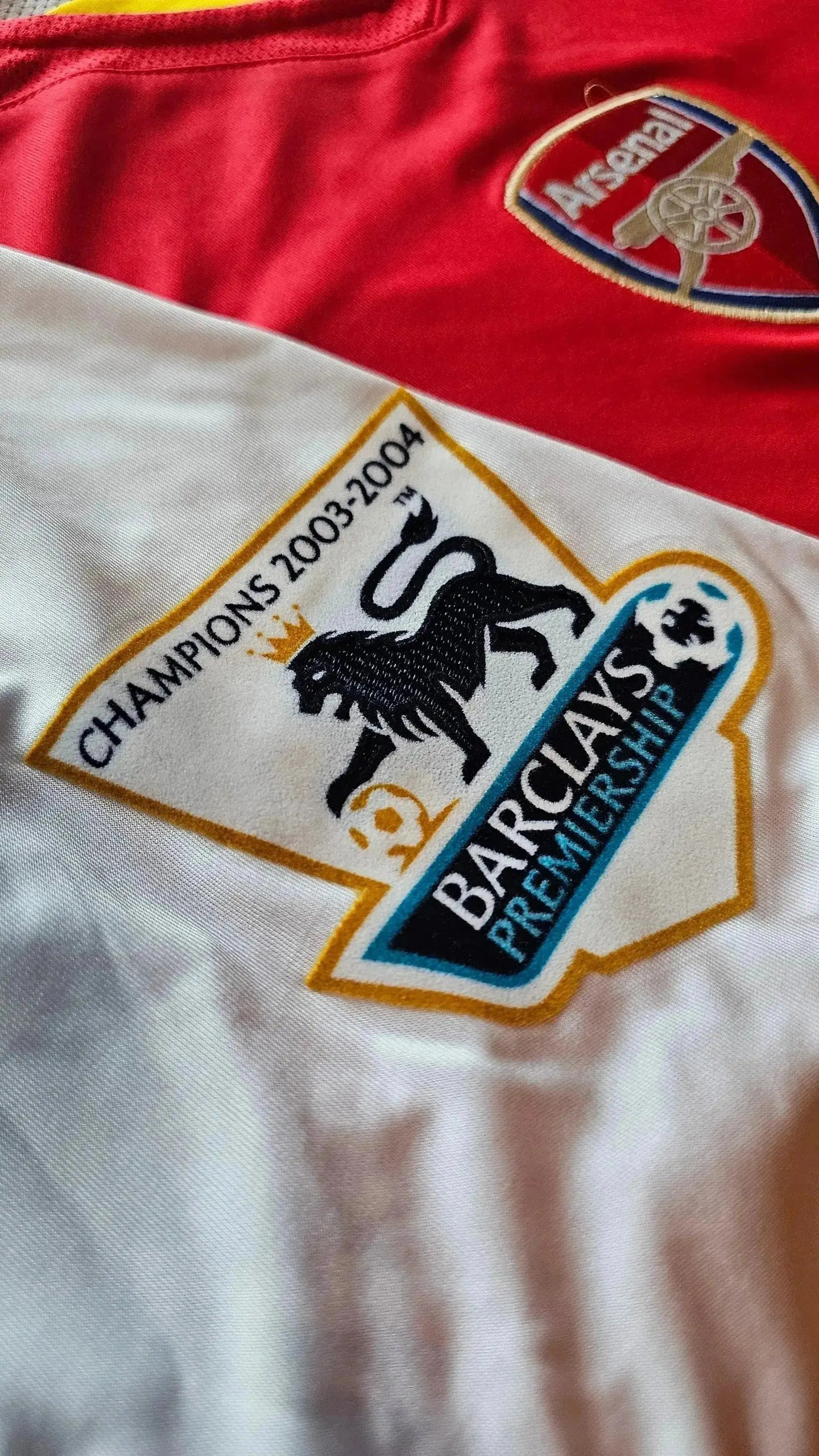 Arsenal crest with 2003-2004 Champions detail and Barclays Premier League logo.