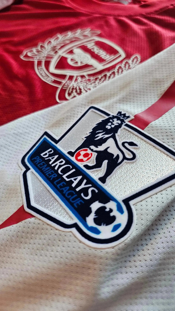 Crest detail featuring Arsenal logo and Premier League badge with lion.