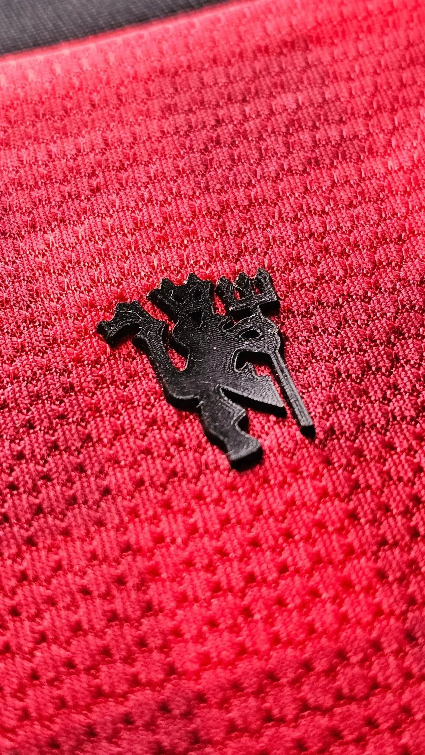 Close-up of the Manchester United crest in black on a red background.