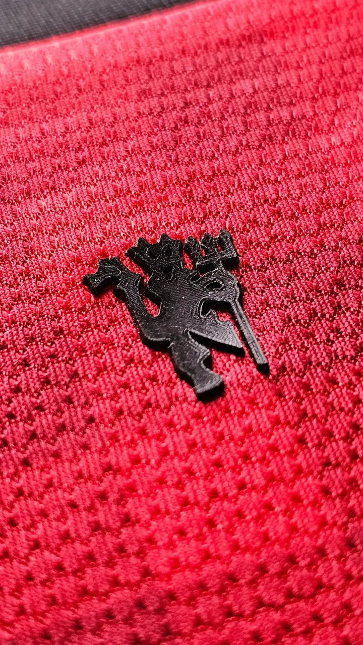Close-up of the Manchester United crest in black on a red background.