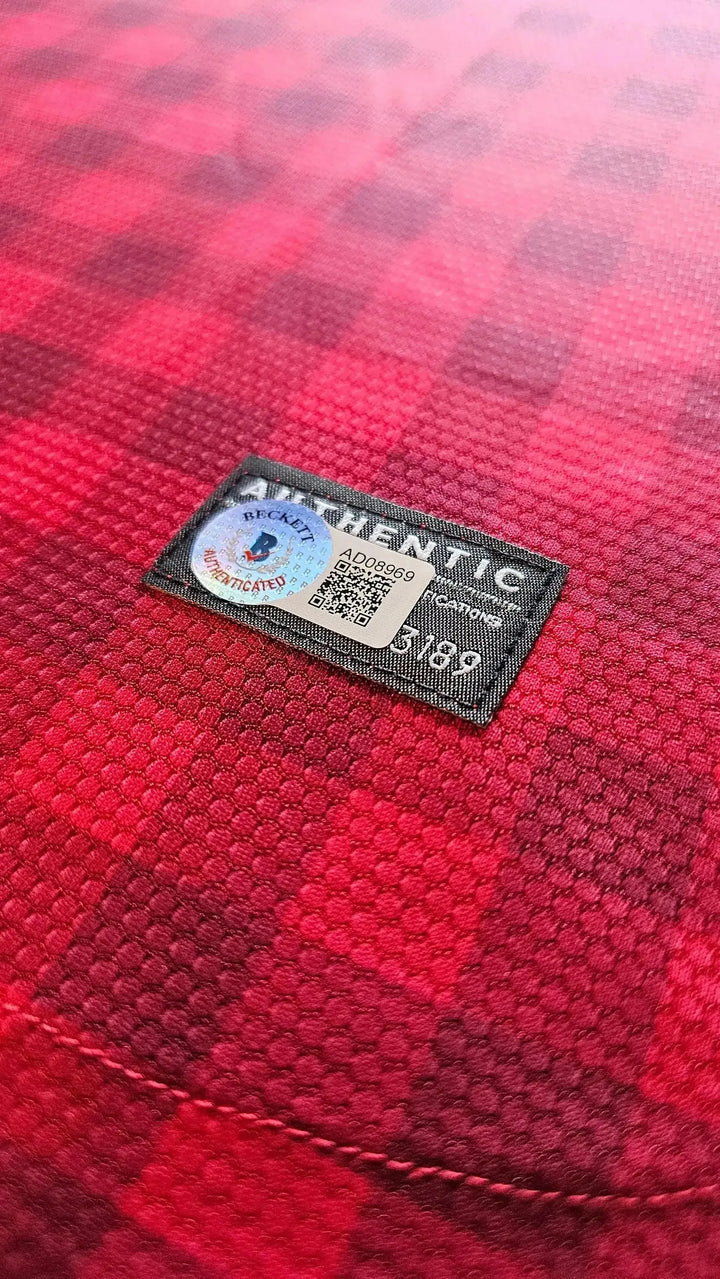 Detail of authenticity tag showing Beckett authentication on red football shirt.