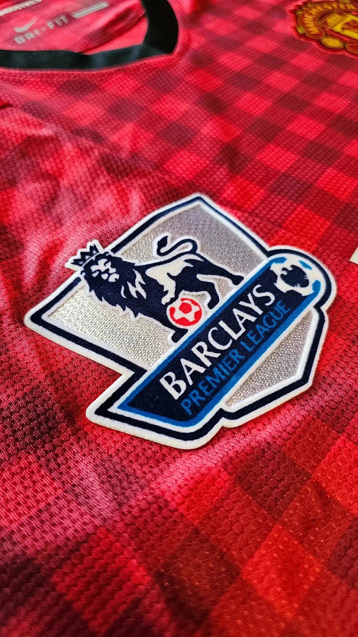 Detail view of the Manchester United crest and Barclays Premier League patch on a red football shirt.