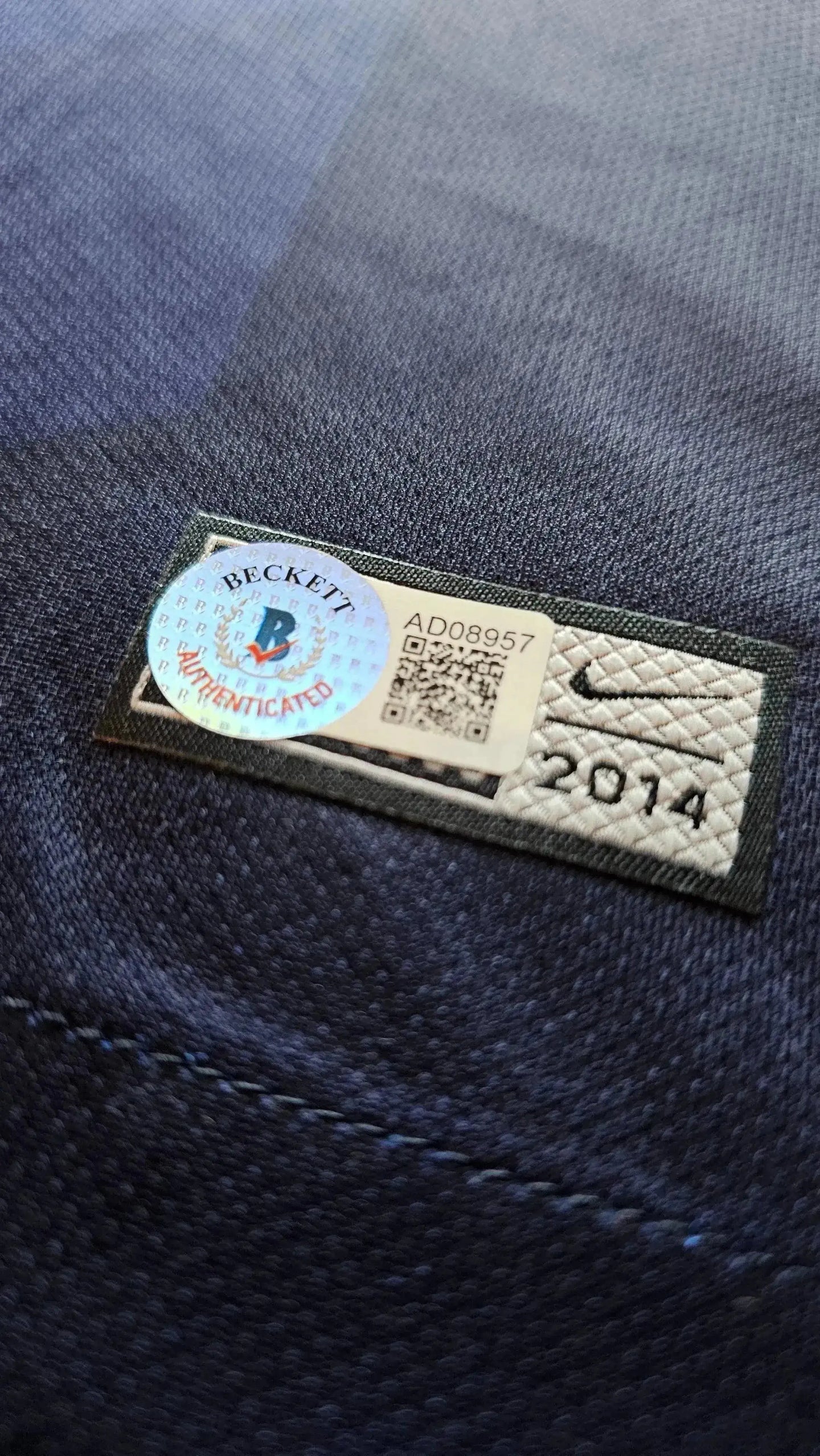 Detail of Beckett authentication sticker on signed football shirt, showing Nike logo and 2014.