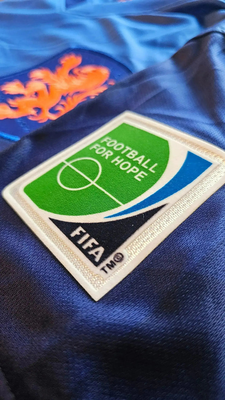 Detail showing the blue and orange crest with the FIFA Football for Hope badge.