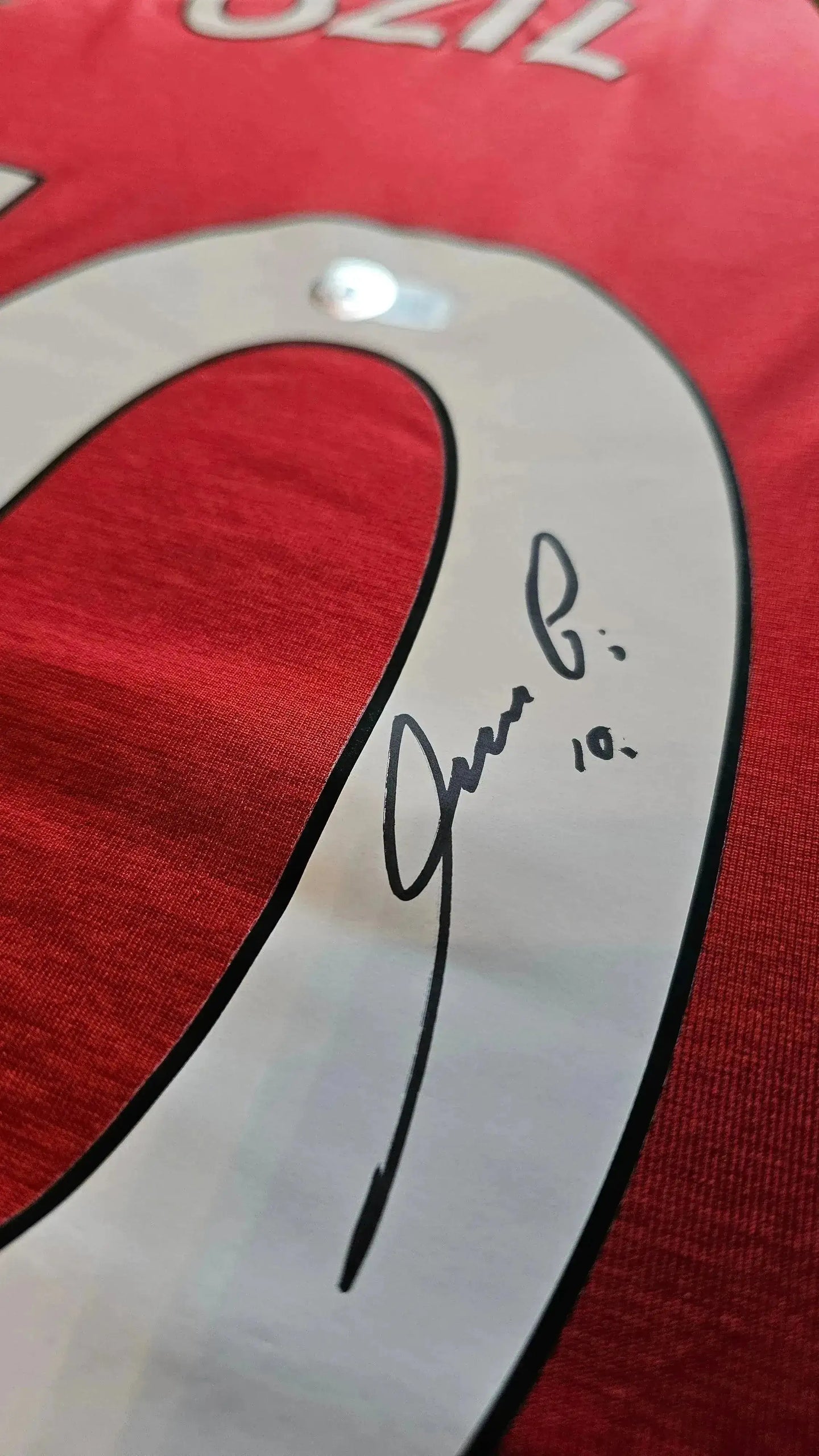 Close-up of the No. 10 on the Mesut Özil signed soccer jersey, featuring Özil's signature.