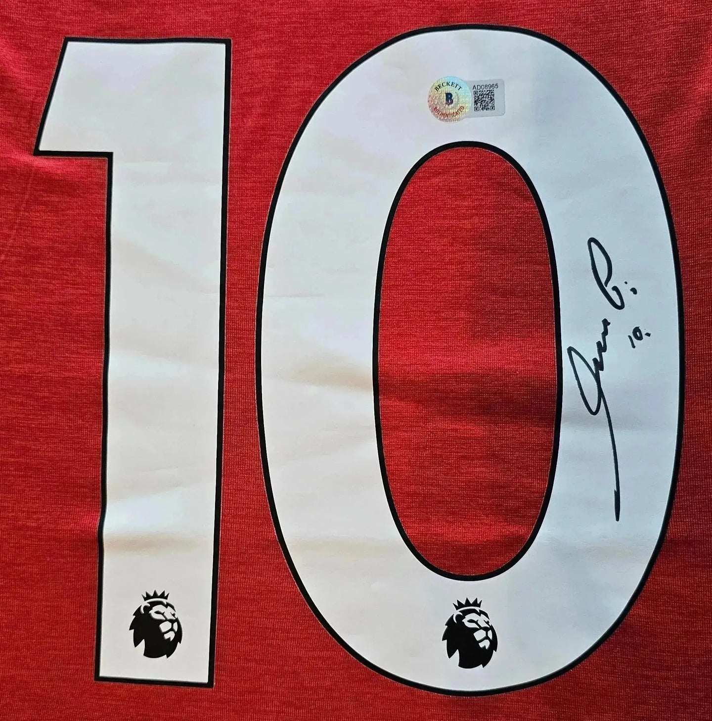 Red jersey featuring No. 10 and signature of Mesut Özil with Premier League logo.