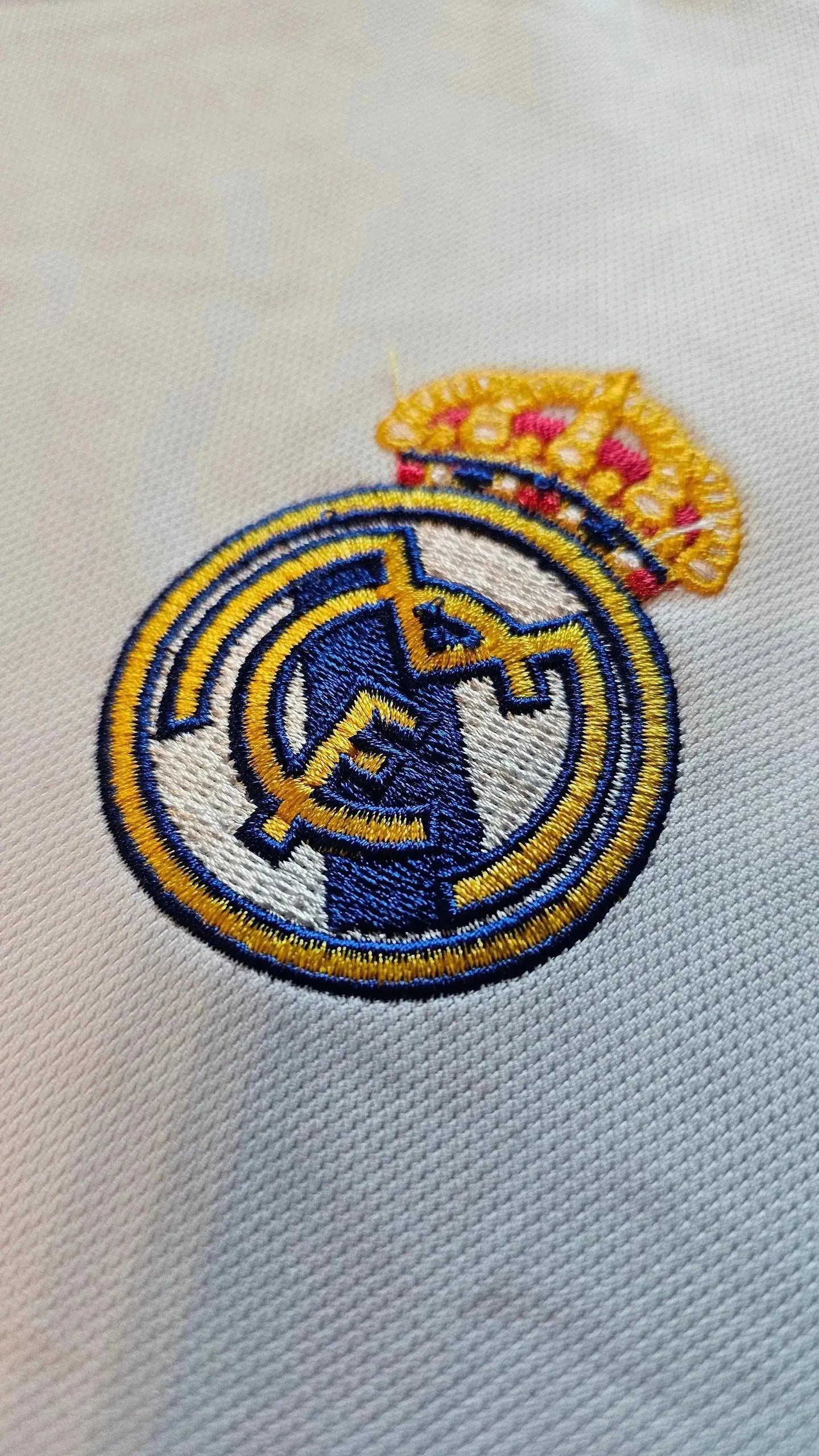 Detail of the Real Madrid crest embroidered in blue, gold, and white with a crown.