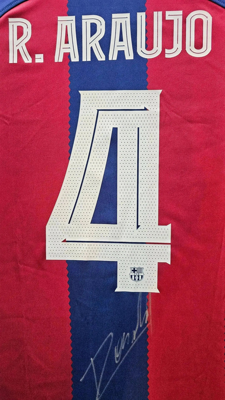 Back view featuring R. Araújo, No. 4, and a visible signature on a striped blue and red football shirt.