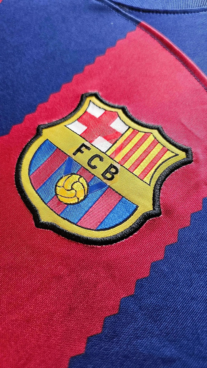 Close-up of FC Barcelona crest featuring yellow embroidery and stripes on blue and red fabric.