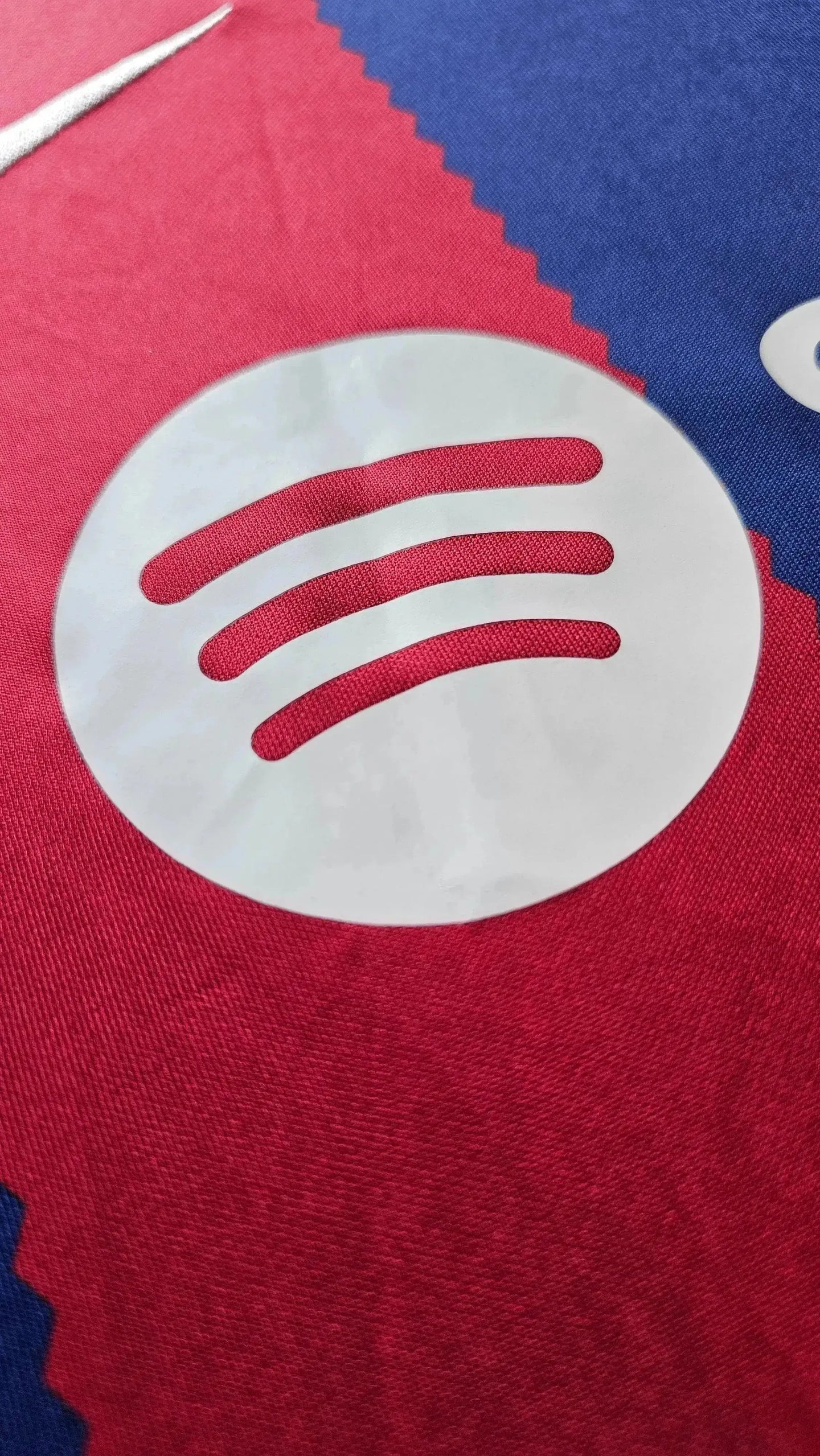 Detail showing the white Spotify logo on red and blue fabric of the Barcelona football shirt.