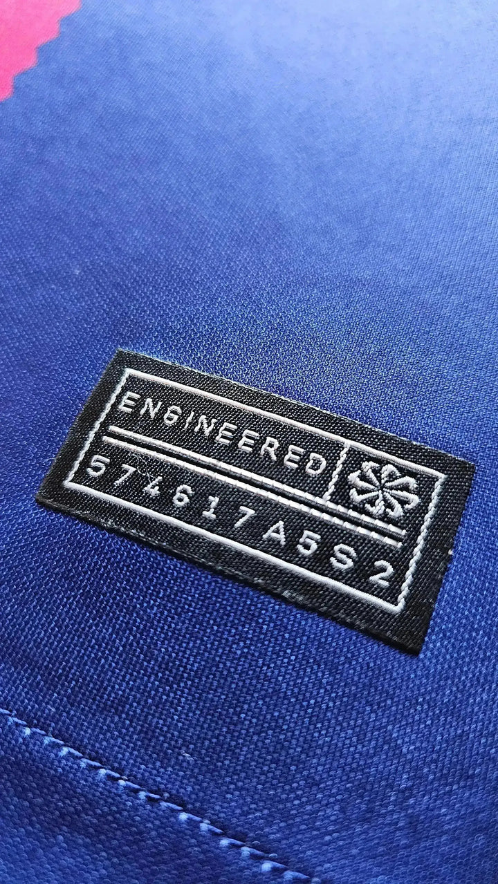 Close-up of tag showing 'ENGINEERED' and code '574617A5S2' on a blue football shirt.