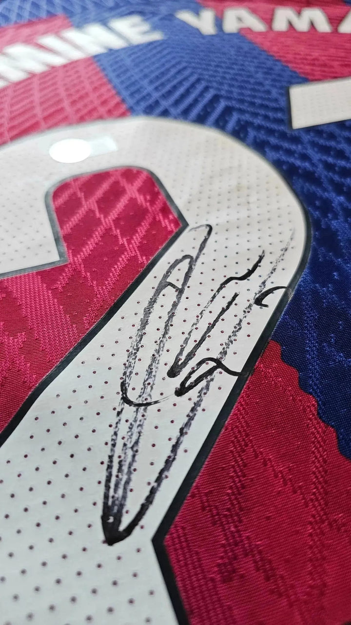 Close-up of No. 27 with Lamine Yamal signature on red and blue Barcelona football shirt.