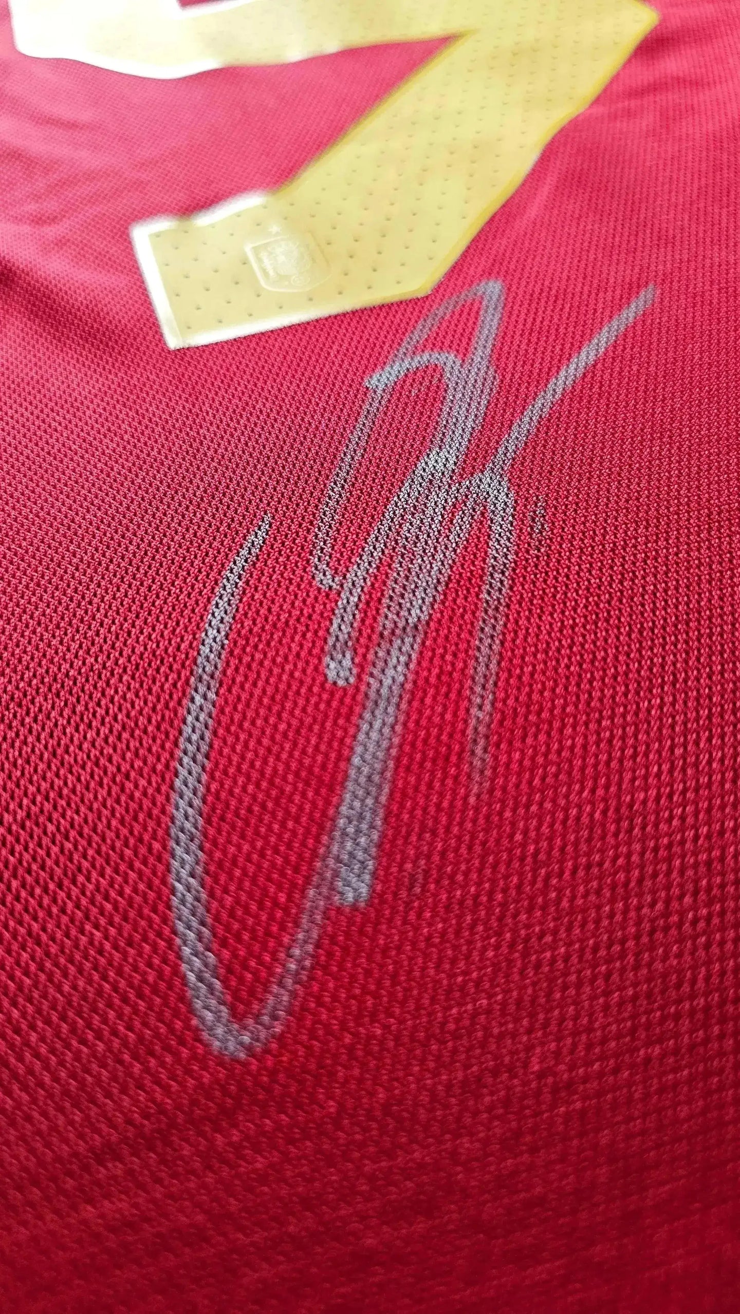 Close-up of Lamine Yamal's signature on the red Spain 2024 soccer jersey beneath the No. 19.