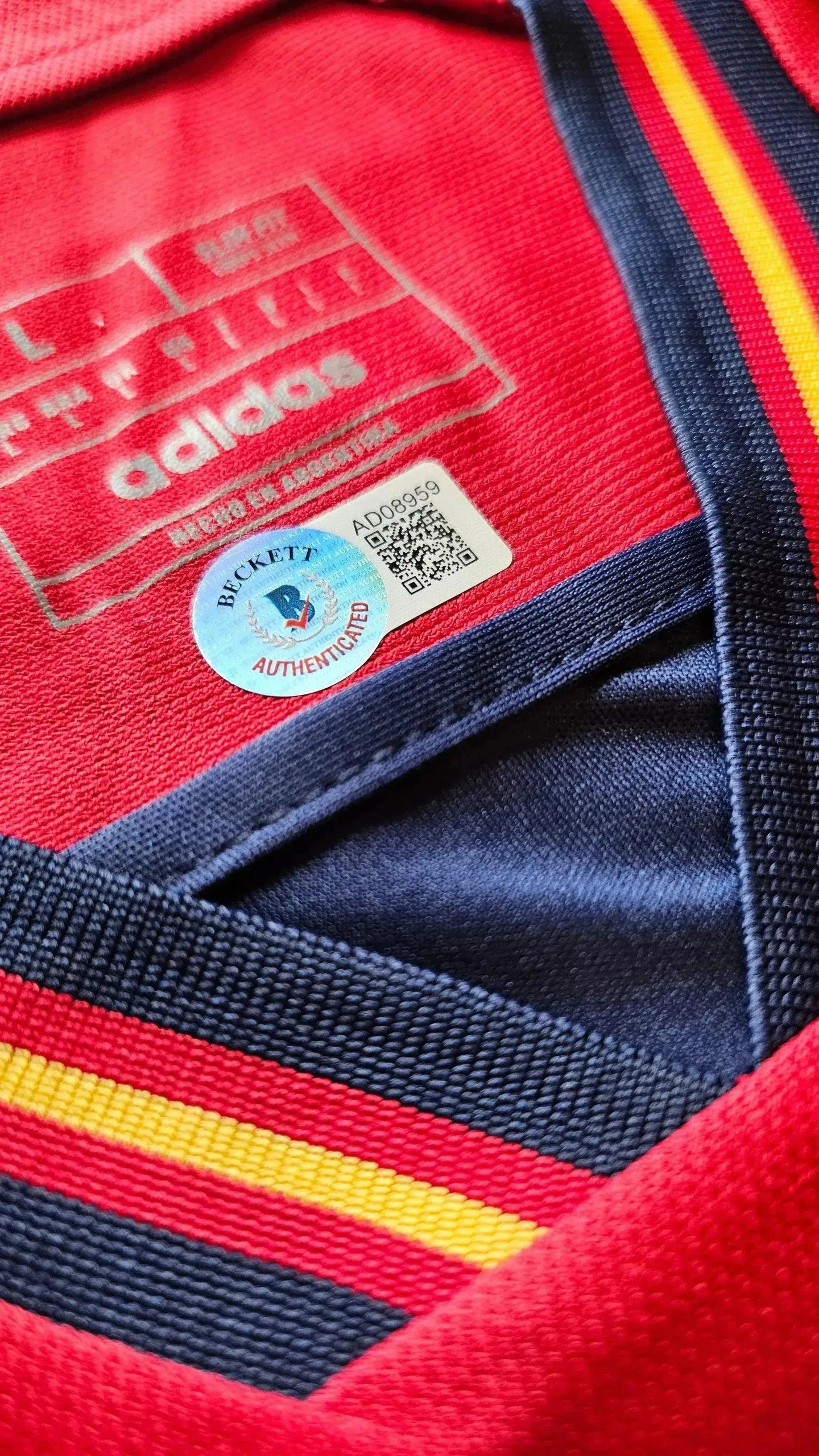 Detail view showing adidas label and Beckett authentication sticker on signed soccer jersey.