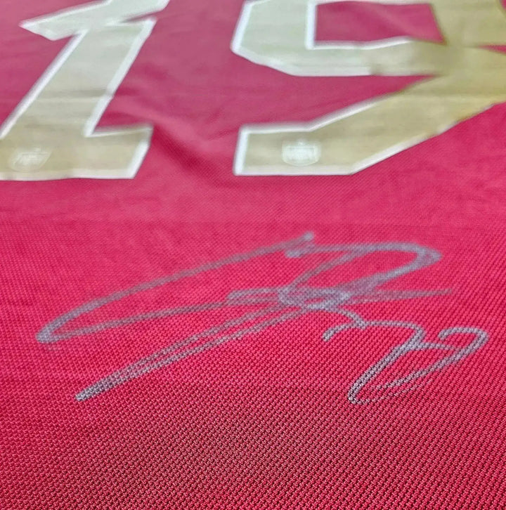 Close-up of No. 19 with visible signature on a red football shirt.
