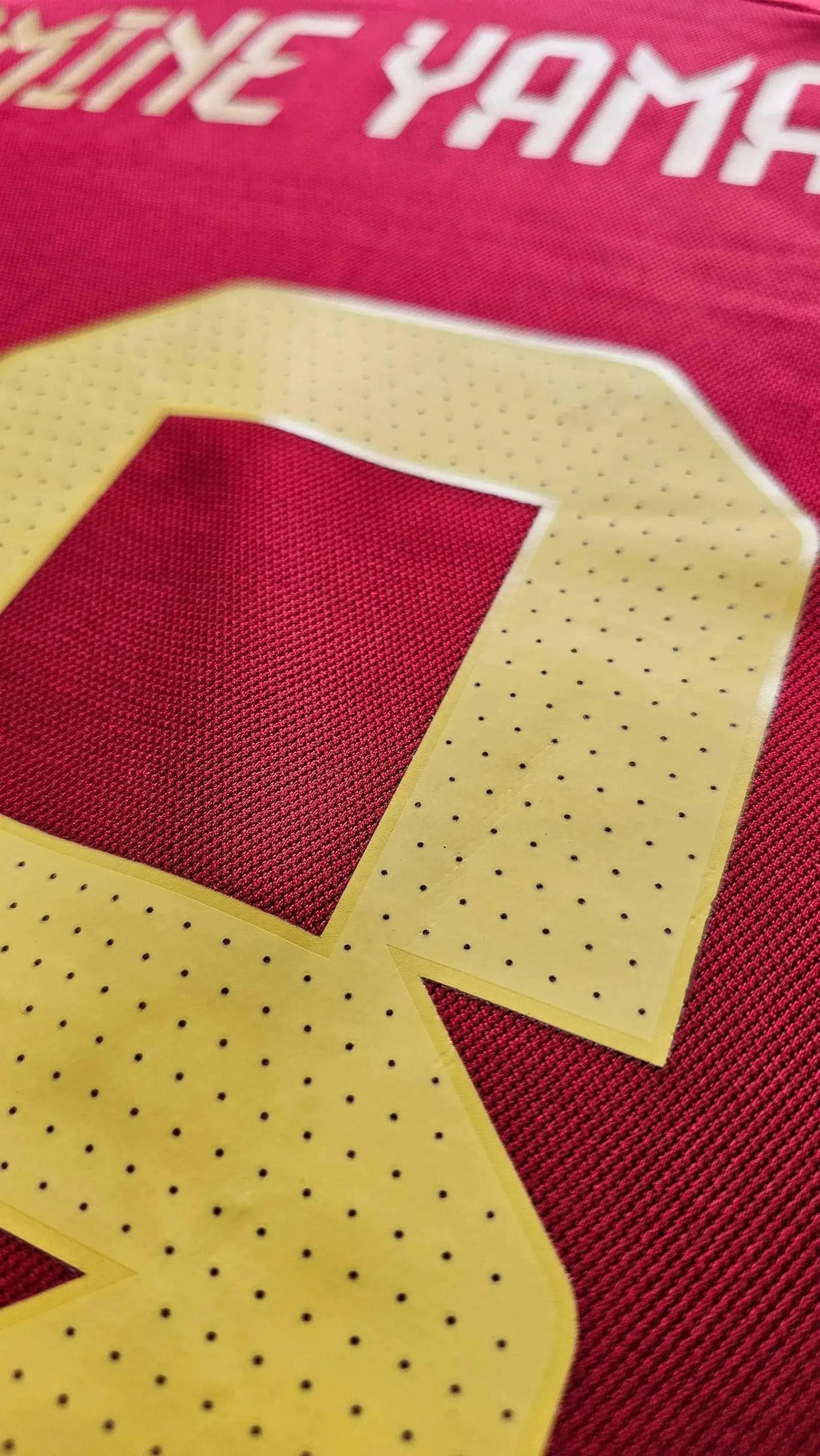 Close-up showing Lamine Yamal and No. 19 on a red soccer jersey with yellow details.